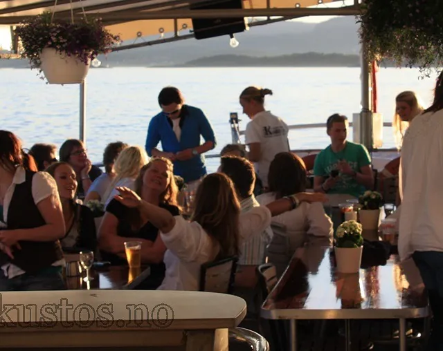 Gruppe mennesker nyter kveldssol og drikke i sosialt lag på båttur.