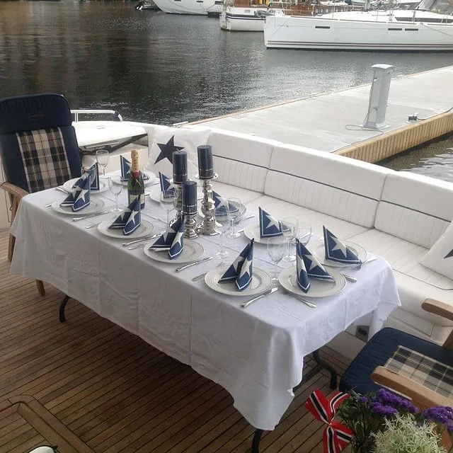 Festpyntet bord med stjernedekor og flagg, plassert på yachtens akterdekk.