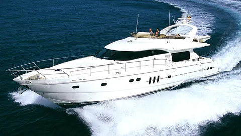 Stor motorbåt i fart over åpent hav med skumsprøyt og passasjerer på øverste dekk