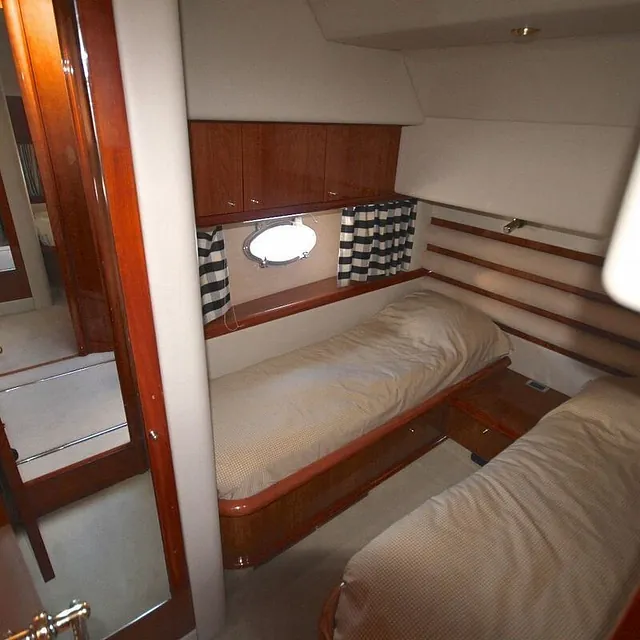 Lugar med to enkeltsenger, skap og koøye med stripete gardiner.