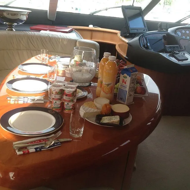 Frokostbord med ost, juice, yoghurt og frukt dekket på i yachtens salong.