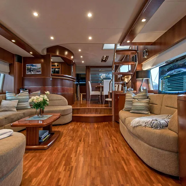 Salong med utsikt mot kjøkken og spiseplass, TV på høyre side og blomster på bordet